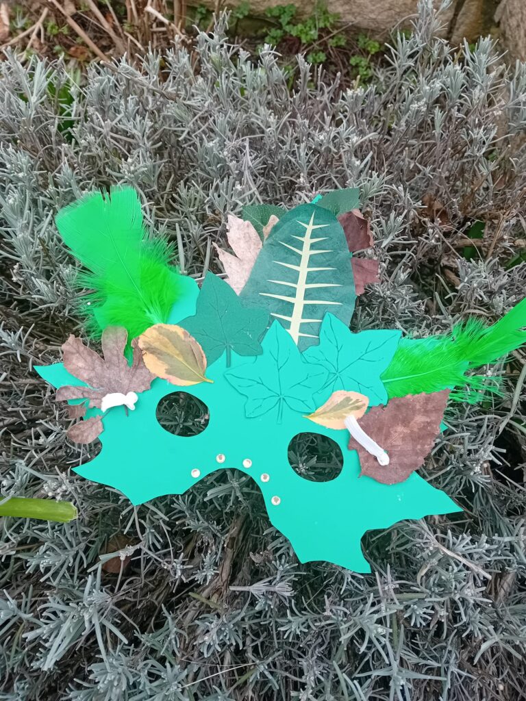Photo of a nature inspired super hero mask. It is mostly green with leaf decorations